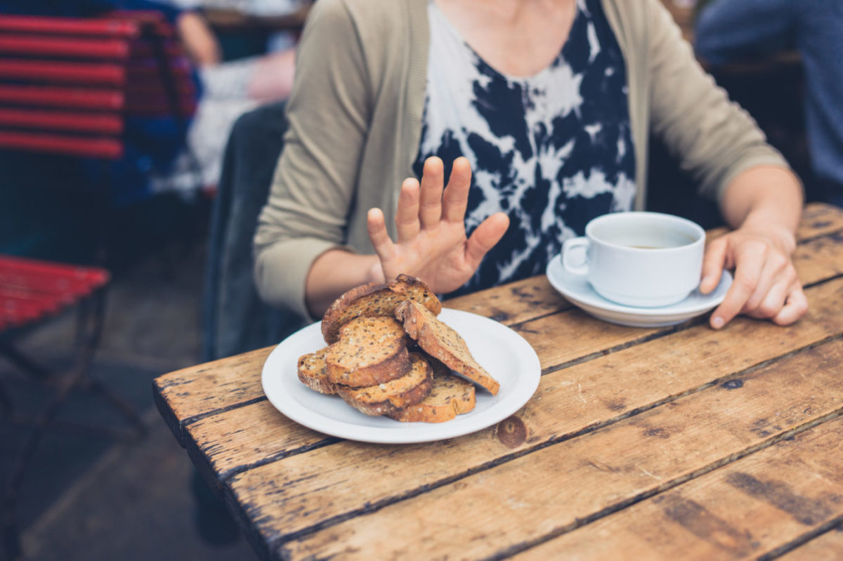 Young woman on gluten free diet is saying no thanks to toast in a cafe