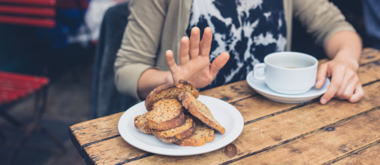 Young woman on gluten free diet is saying no thanks to toast in a cafe